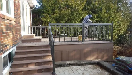 Aluma Contracting installer fitting a black aluminum deck railing on a residential composite deck
