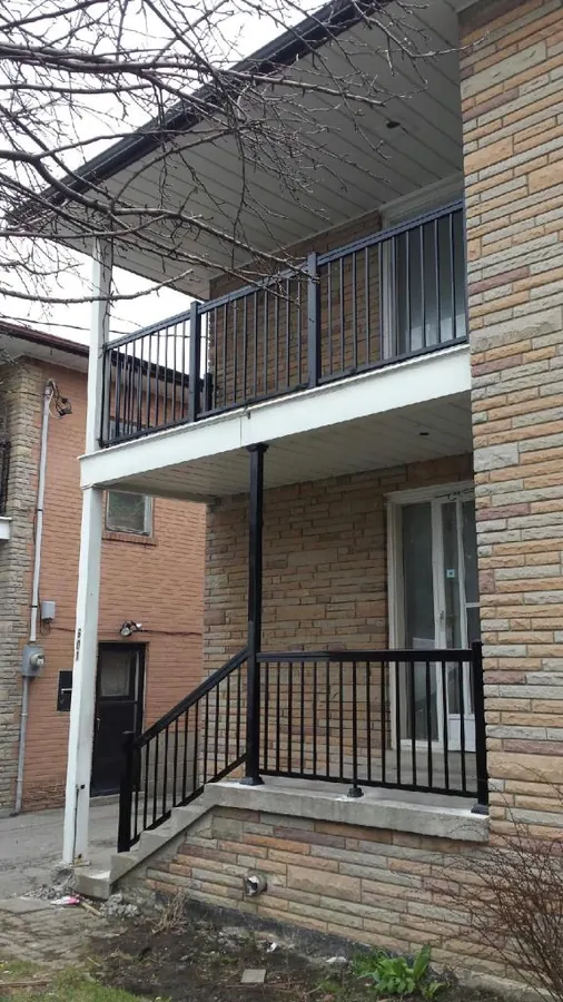 Low black aluminum front-porch railing on light-brick split-level home