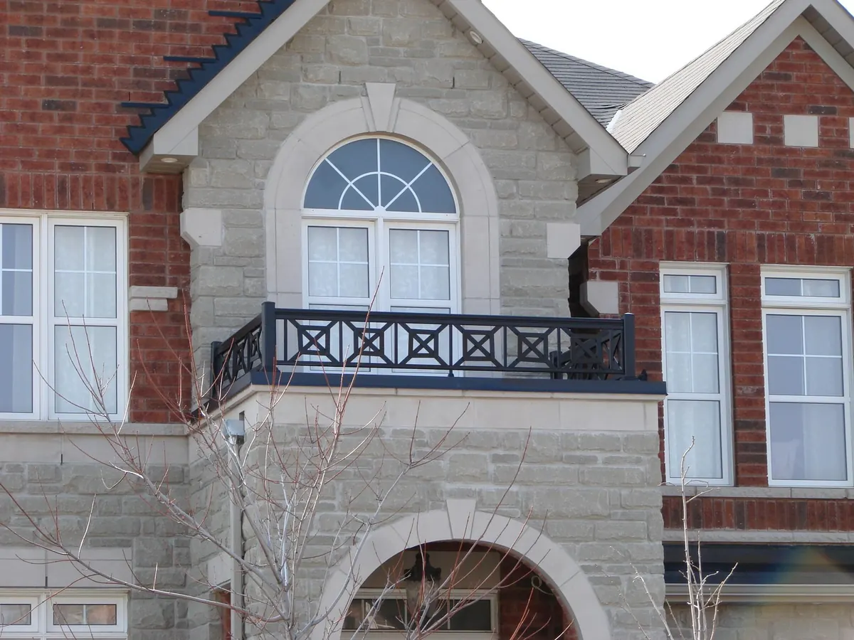 Decorative aluminum Juliet balcony with X-pattern motif on stucco facade