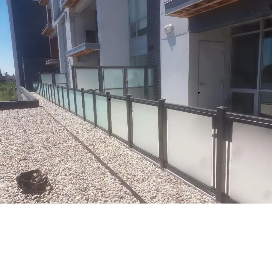 Frosted-glass exterior stair railing with bronze top rail along narrow path
