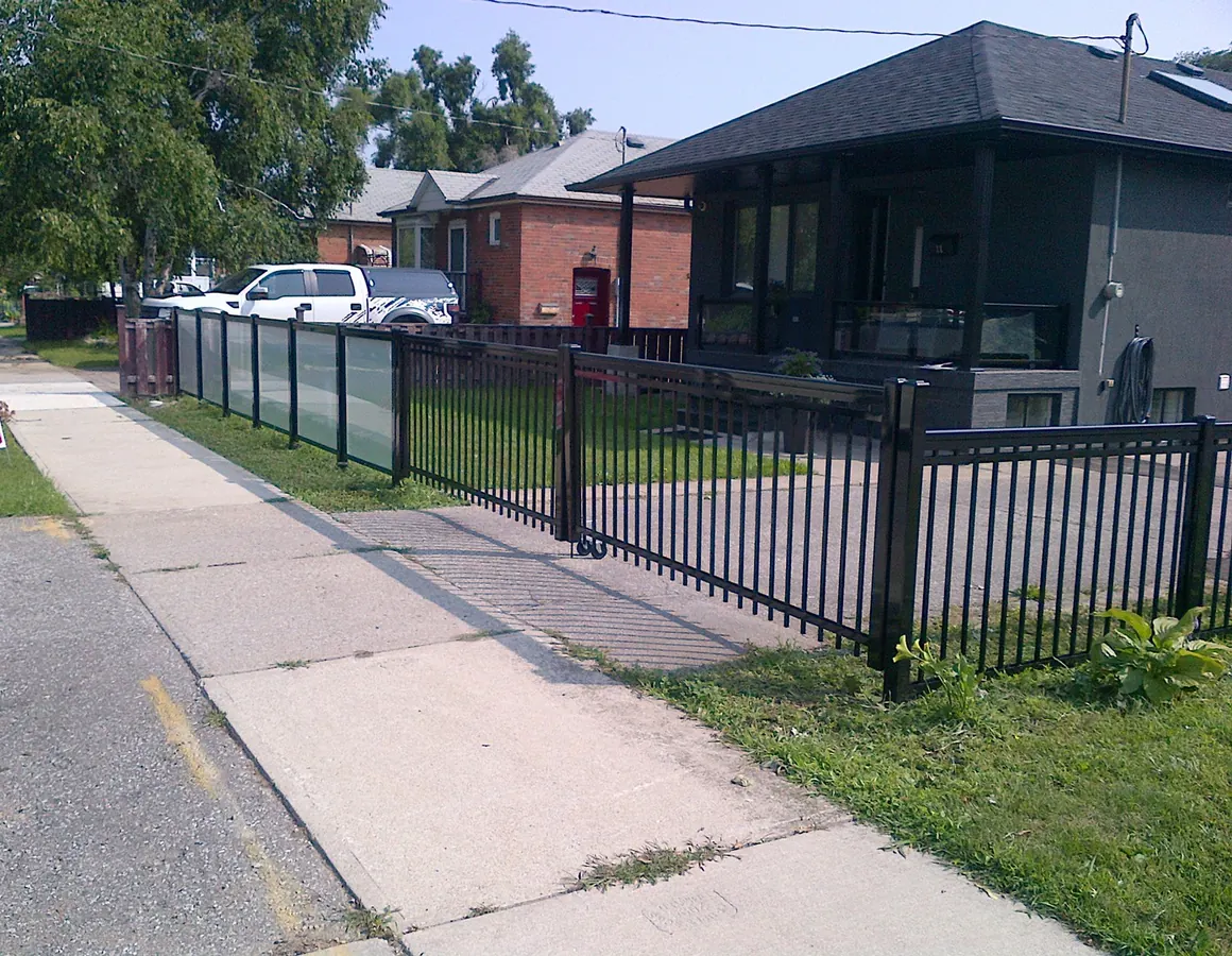 Black aluminum streetfront fence on retaining wall along sidewalk row