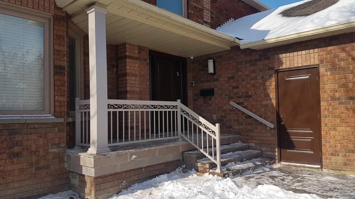 White aluminum-wrapped porch columns with stone-faced base in winter